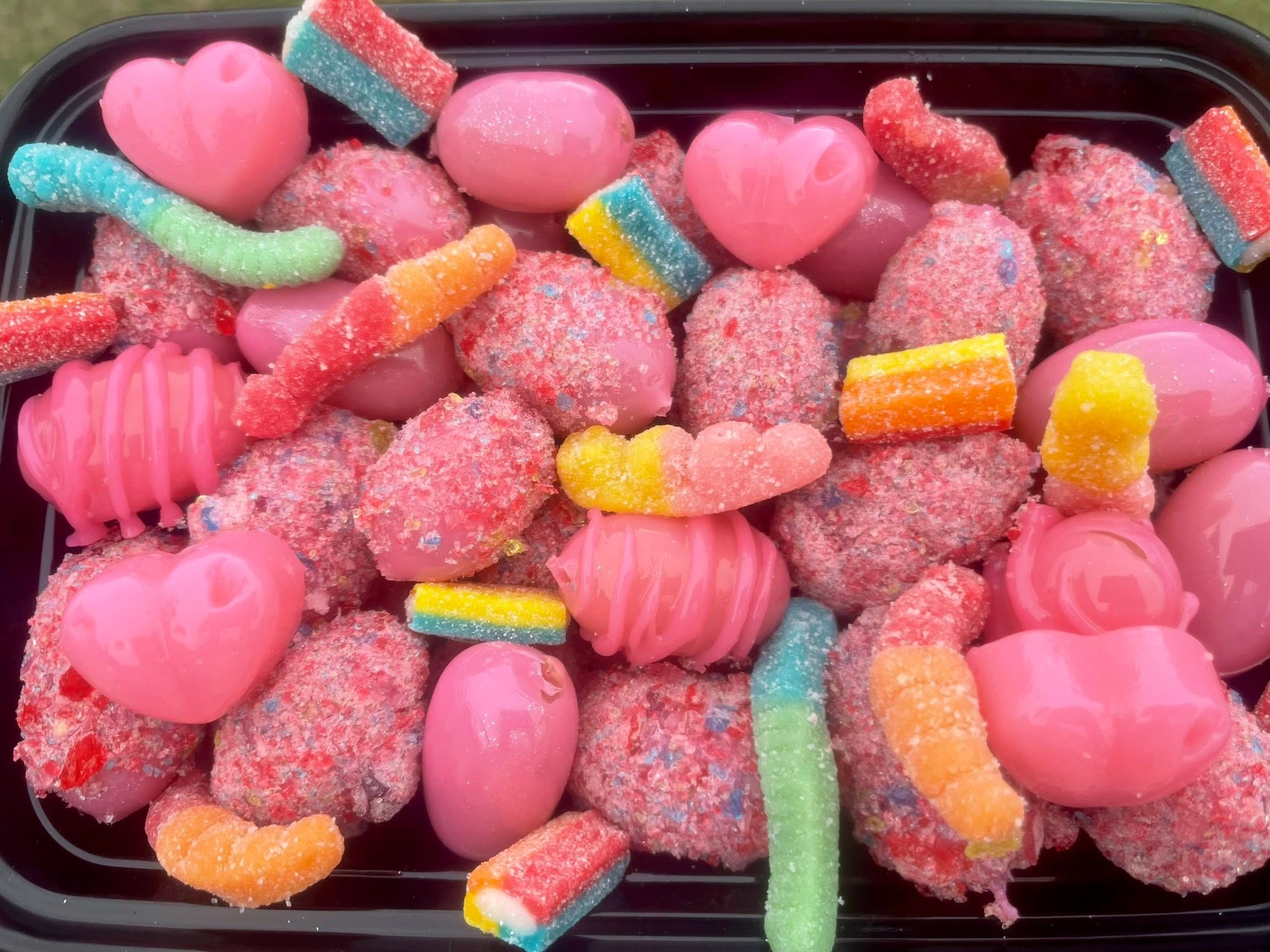 Pink candied fruit with sour gummy worms and candy hearts